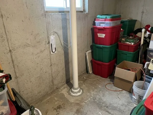 Sealed sub-slab suction point with U-tube manometer in a basement corner