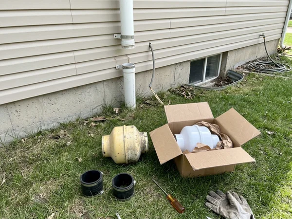 Old radon fan next to its replacement outside an Iowa home
