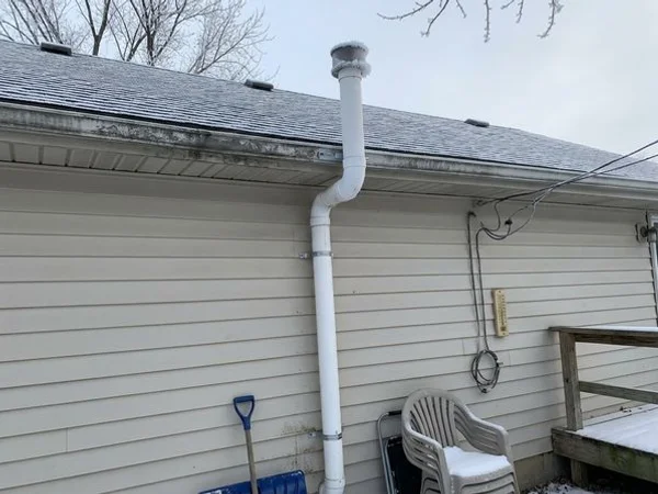 Radon exhaust vent above a roof edge in winter