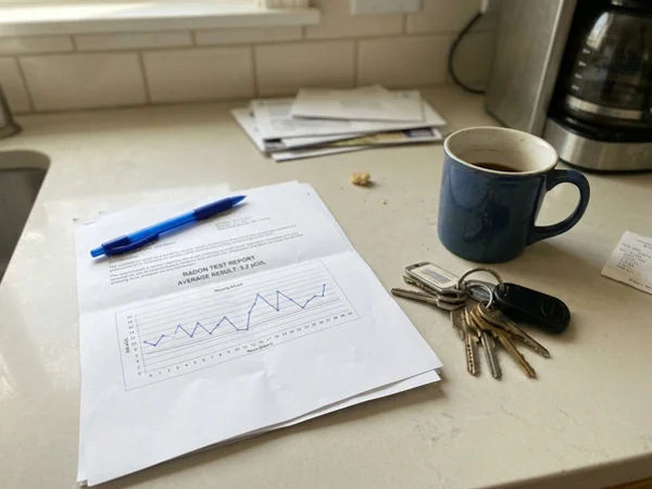 Printed radon test report with hourly chart on a kitchen counter
